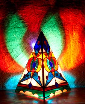 The Harmonic Convergence Pyramid Lamp glows its brilliant design on surrounding walls.